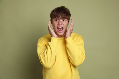Photo of Teenage boy suffering from panic attack on green background