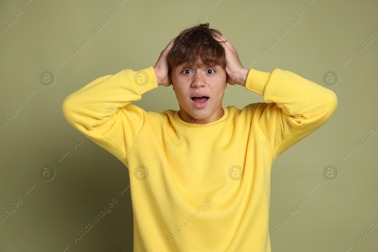 Photo of Teenage boy suffering from panic attack on green background