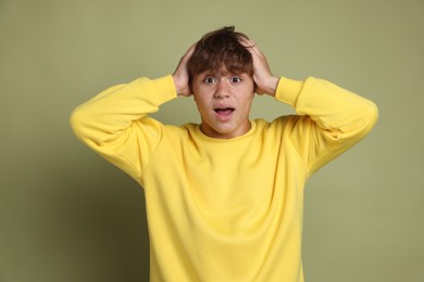 Photo of Teenage boy suffering from panic attack on green background