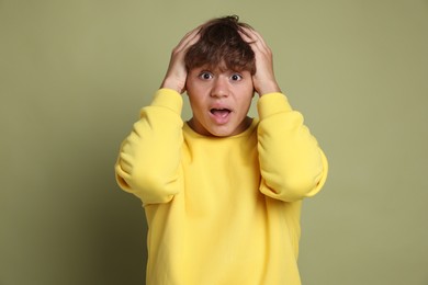 Photo of Teenage boy suffering from panic attack on green background