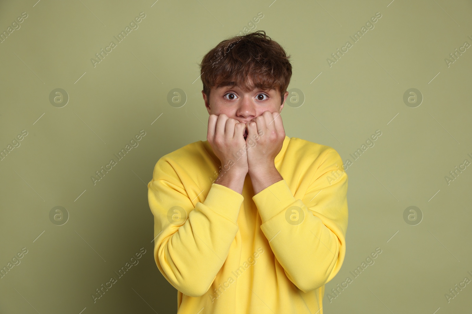 Photo of Teenage boy suffering from panic attack on green background
