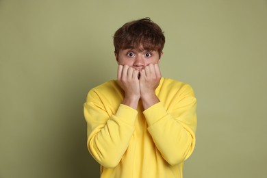 Photo of Teenage boy suffering from panic attack on green background