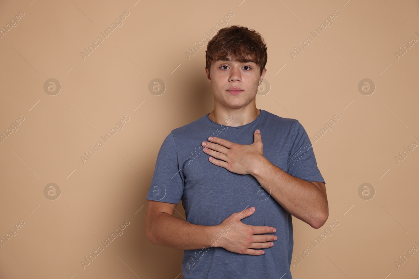 Photo of Teenage boy deep breathing on beige background, space for text. Way to stop panic attack