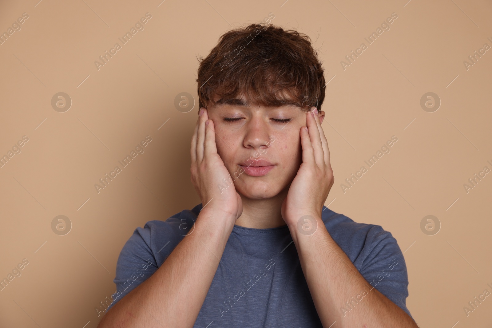 Photo of Teenage boy meditating on beige background. Way to stop panic attack