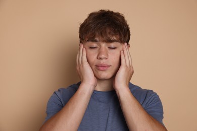 Photo of Teenage boy meditating on beige background. Way to stop panic attack