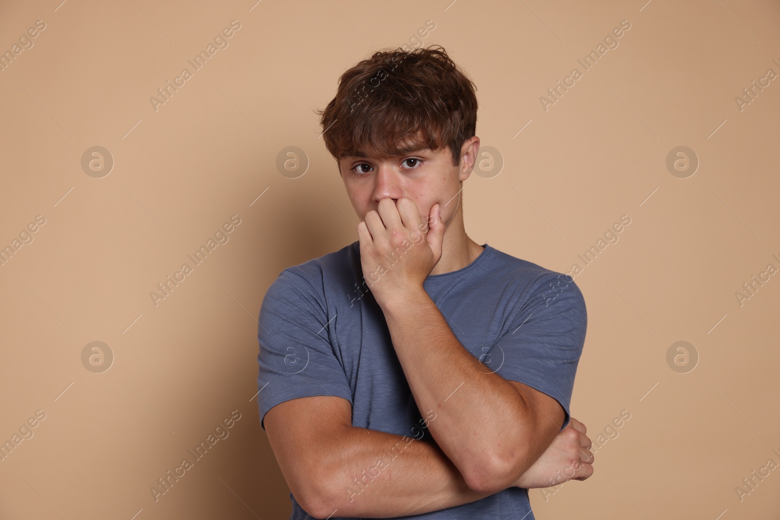 Photo of Teenage boy suffering from panic attack on beige background