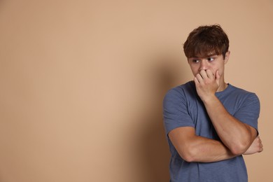 Photo of Teenage boy suffering from panic attack on beige background. Space for text