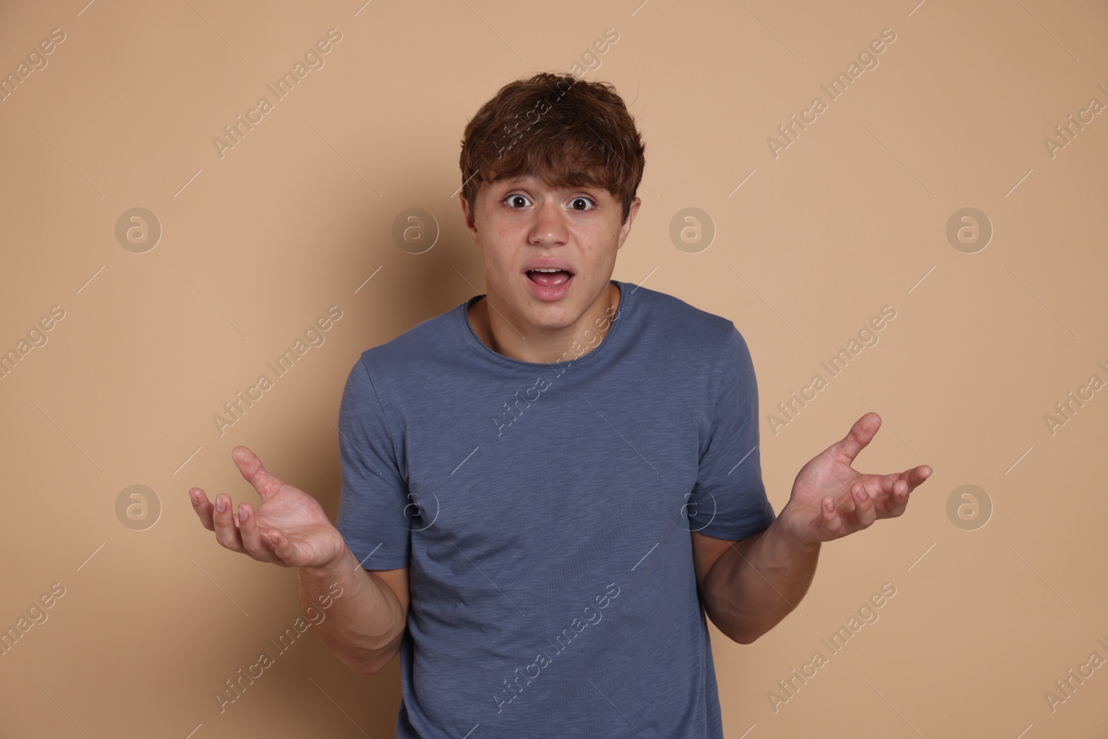 Teenage boy suffering from panic attack on beige background Photo of Teenage boy suffering from panic attack on beige background