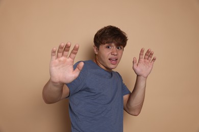 Photo of Teenage boy suffering from panic attack on beige background