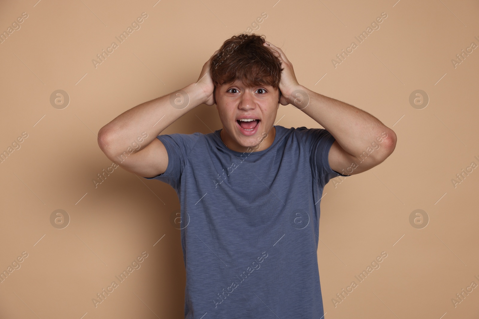 Photo of Teenage boy suffering from panic attack on beige background