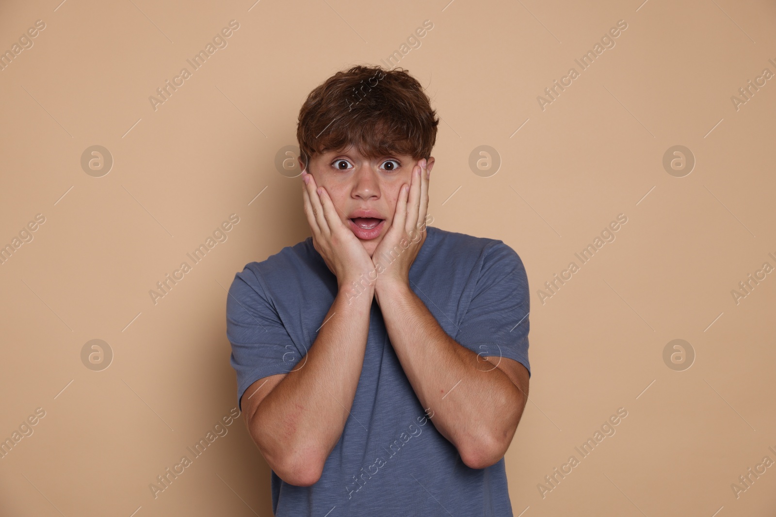 Photo of Teenage boy suffering from panic attack on beige background