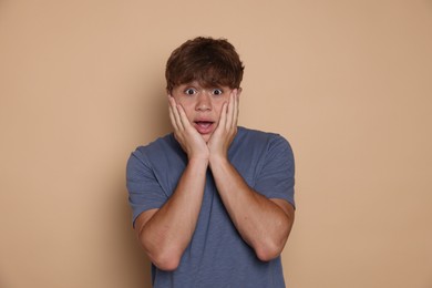 Photo of Teenage boy suffering from panic attack on beige background