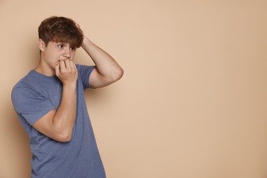 Photo of Teenage boy suffering from panic attack on beige background. Space for text