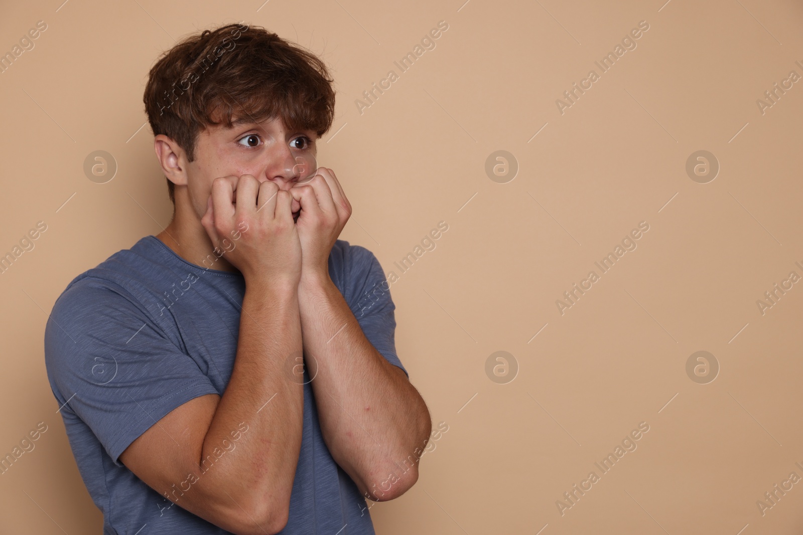 Photo of Teenage boy suffering from panic attack on beige background. Space for text