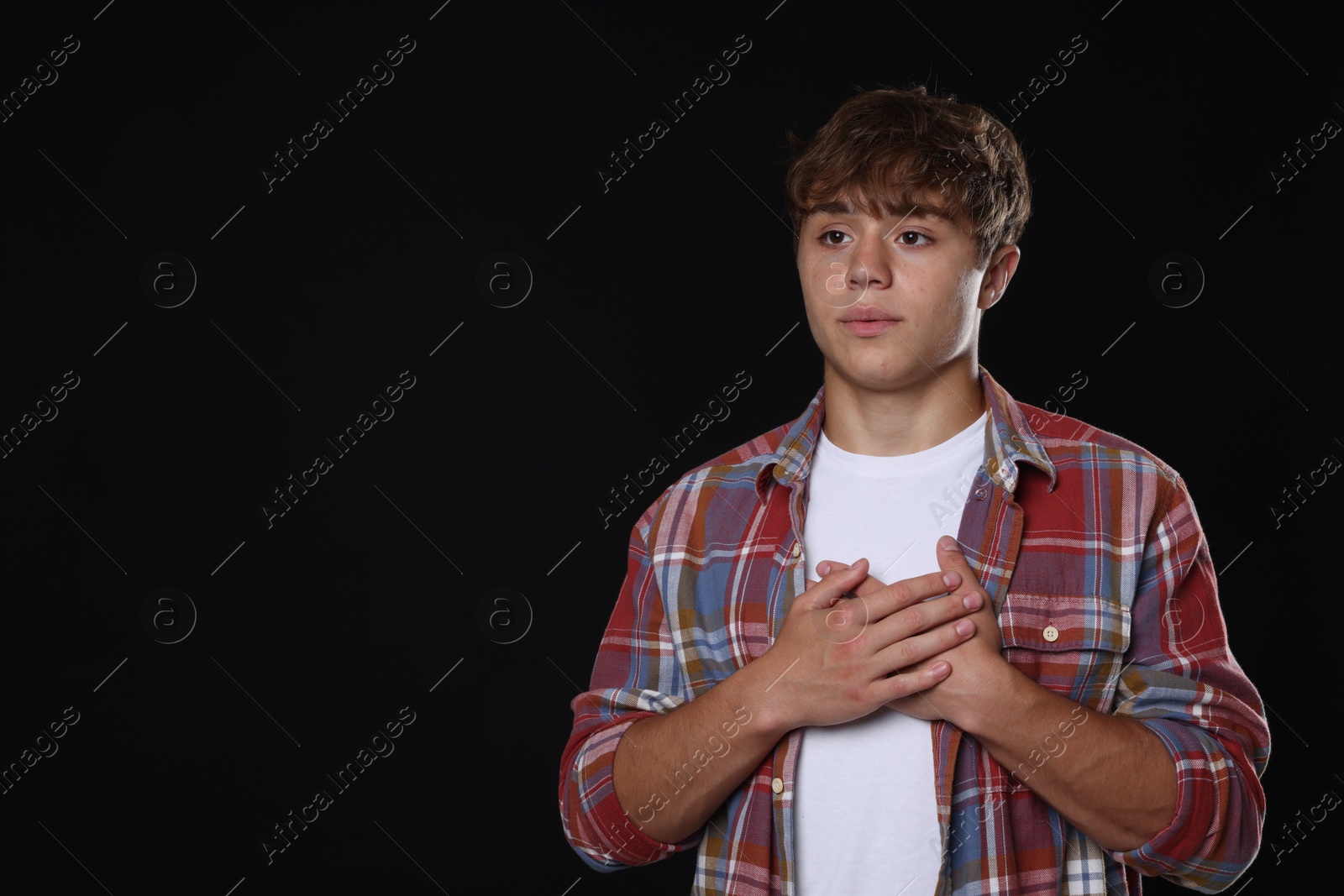 Photo of Teenage boy deep breathing on black background, space for text. Way to stop panic attack