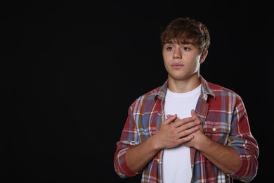 Photo of Teenage boy deep breathing on black background, space for text. Way to stop panic attack