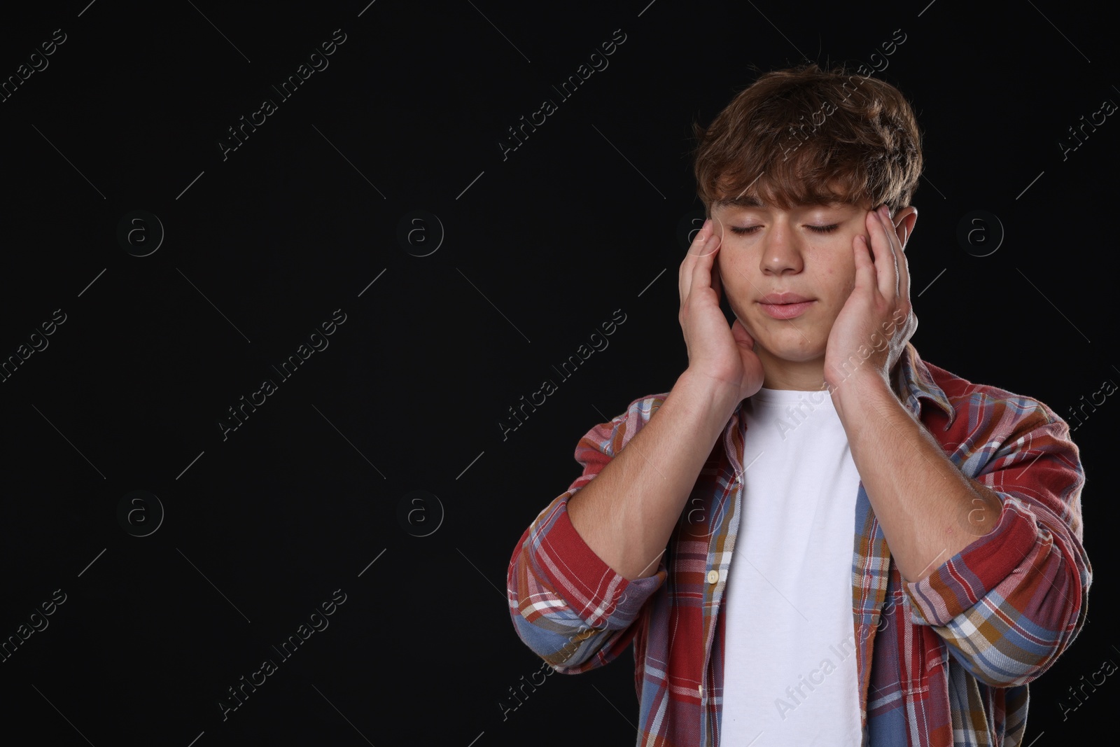 Photo of Teenage boy meditating on black background, space for text. Way to stop panic attack