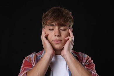Photo of Teenage boy meditating on black background. Way to stop panic attack