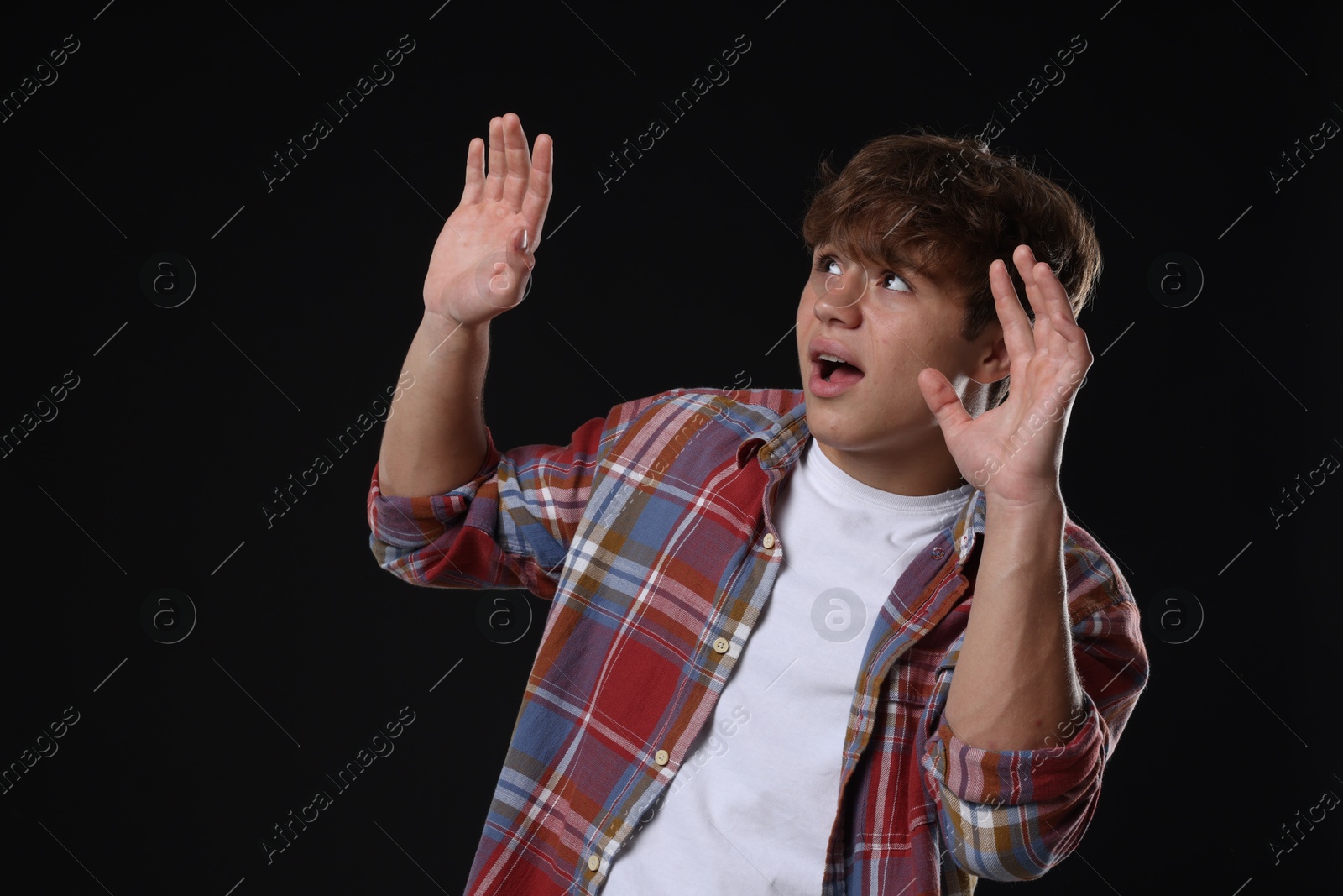 Photo of Teenage boy suffering from panic attack on black background