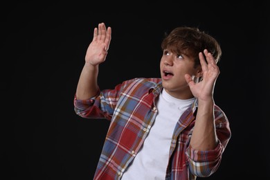 Photo of Teenage boy suffering from panic attack on black background