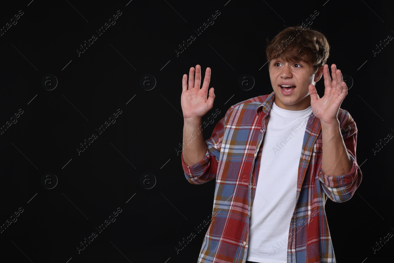 Photo of Teenage boy suffering from panic attack on black background. Space for text