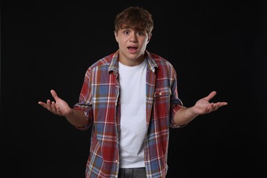 Photo of Teenage boy suffering from panic attack on black background
