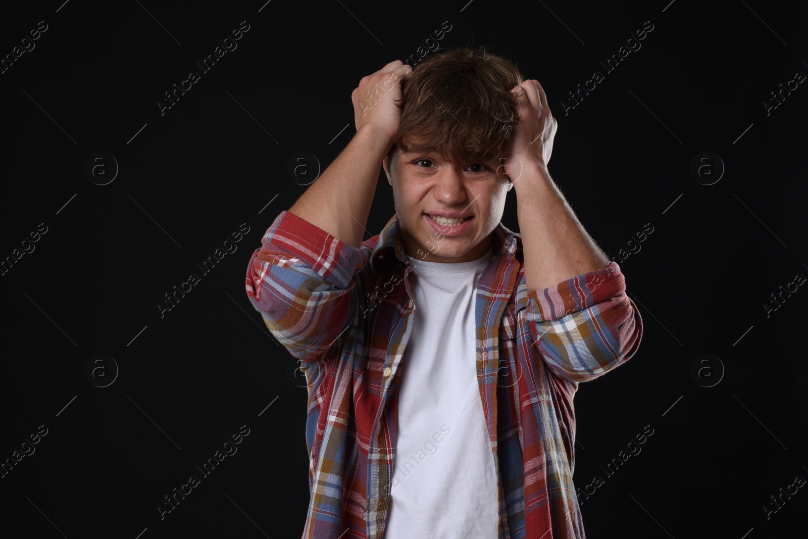 Photo of Teenage boy suffering from panic attack on black background