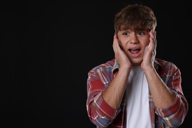 Photo of Teenage boy suffering from panic attack on black background. Space for text