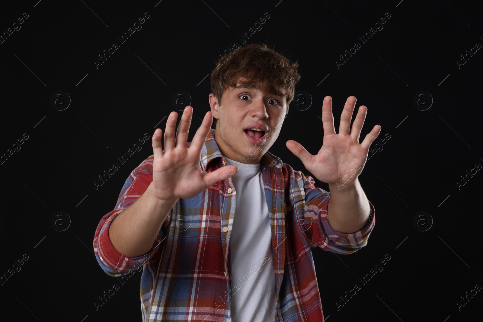 Teenage boy suffering from panic attack on black background Photo of Teenage boy suffering from panic attack on black background