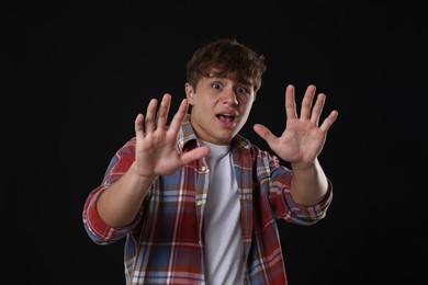 Photo of Teenage boy suffering from panic attack on black background