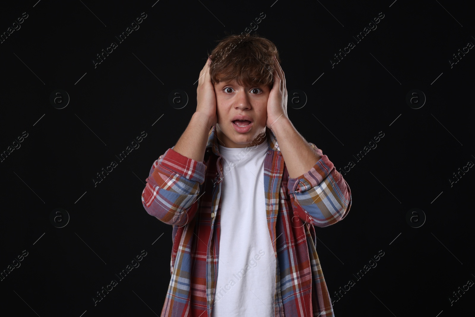 Photo of Teenage boy suffering from panic attack on black background