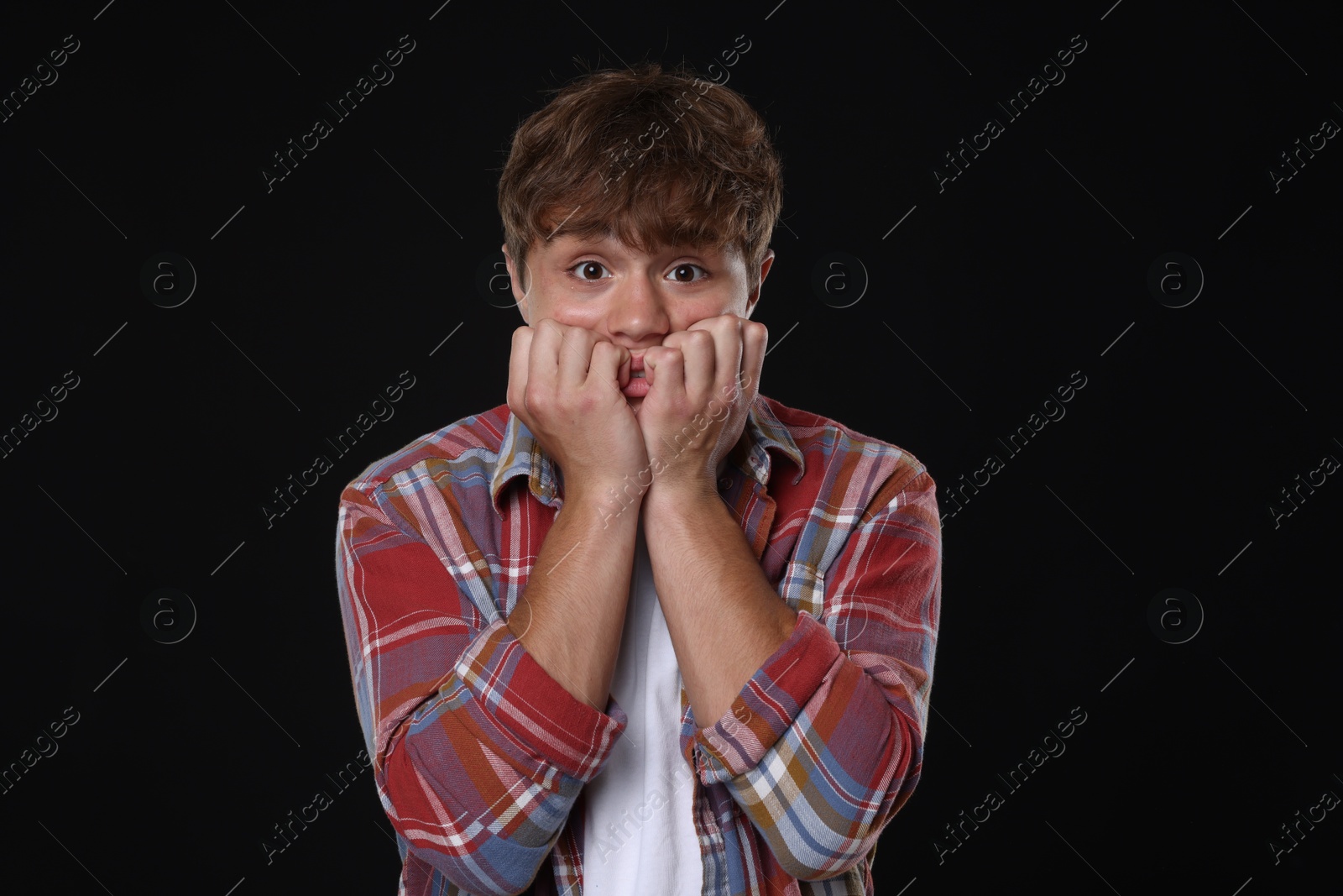 Teenage boy suffering from panic attack on black background Photo of Teenage boy suffering from panic attack on black background