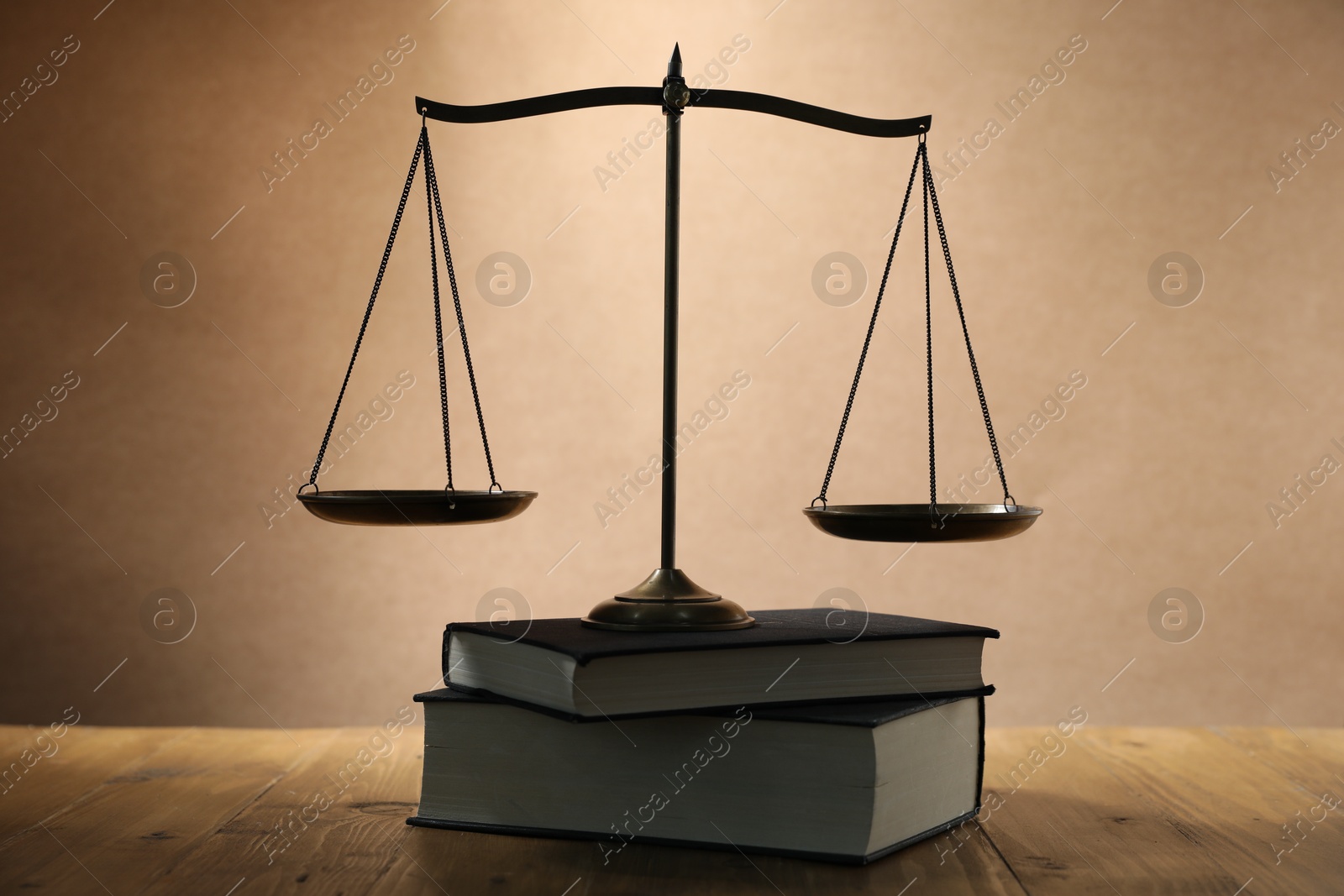 Photo of Scales of justice and books on wooden table against beige background