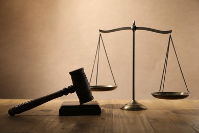 Photo of Gavel and scales of justice on wooden table against beige background