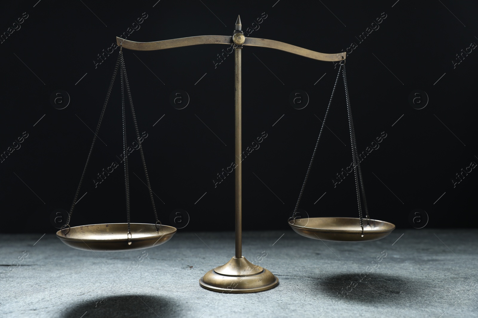Photo of Scales of justice on grey table against black background