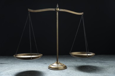 Photo of Scales of justice on grey table against black background