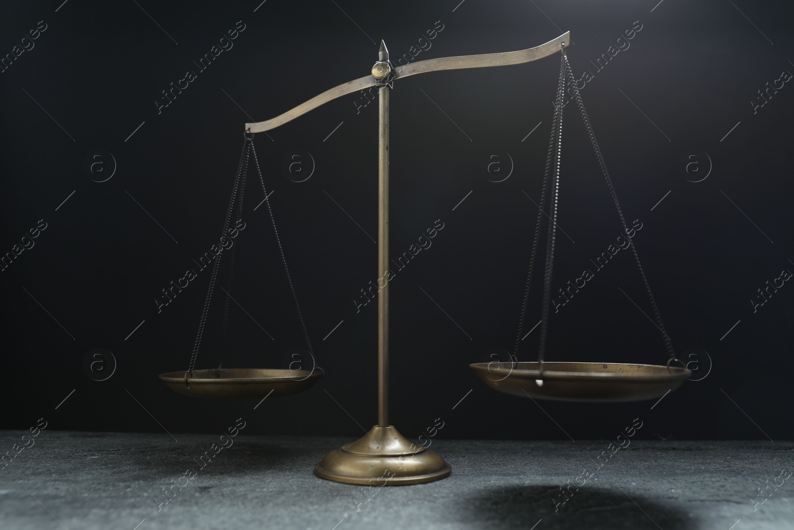 Scales of justice on grey table against black background Photo of Scales of justice on grey table against black background