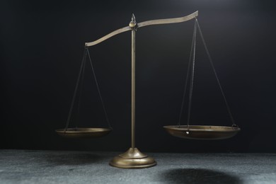 Photo of Scales of justice on grey table against black background