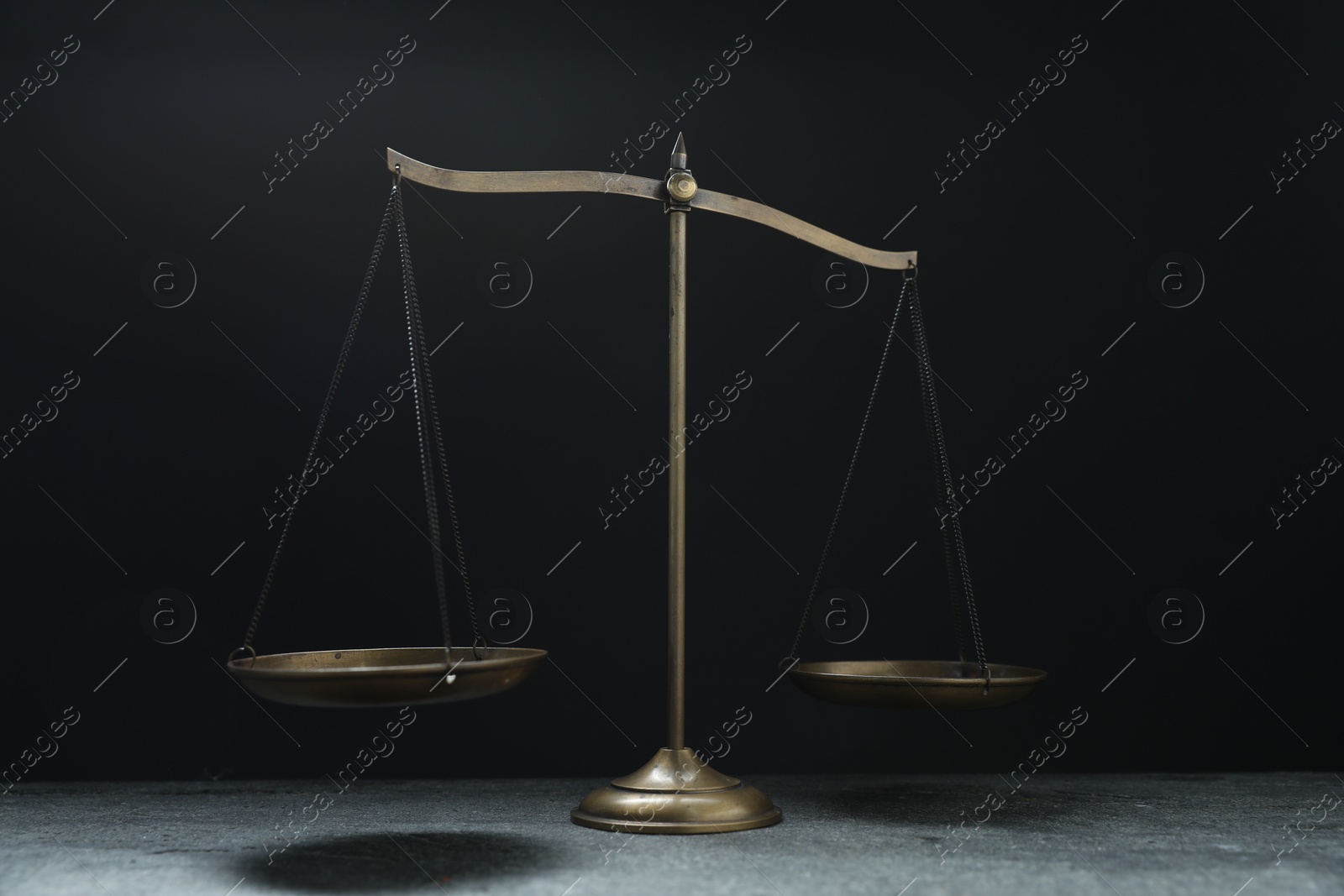 Photo of Scales of justice on grey table against black background