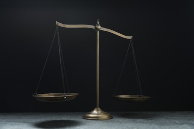 Photo of Scales of justice on grey table against black background