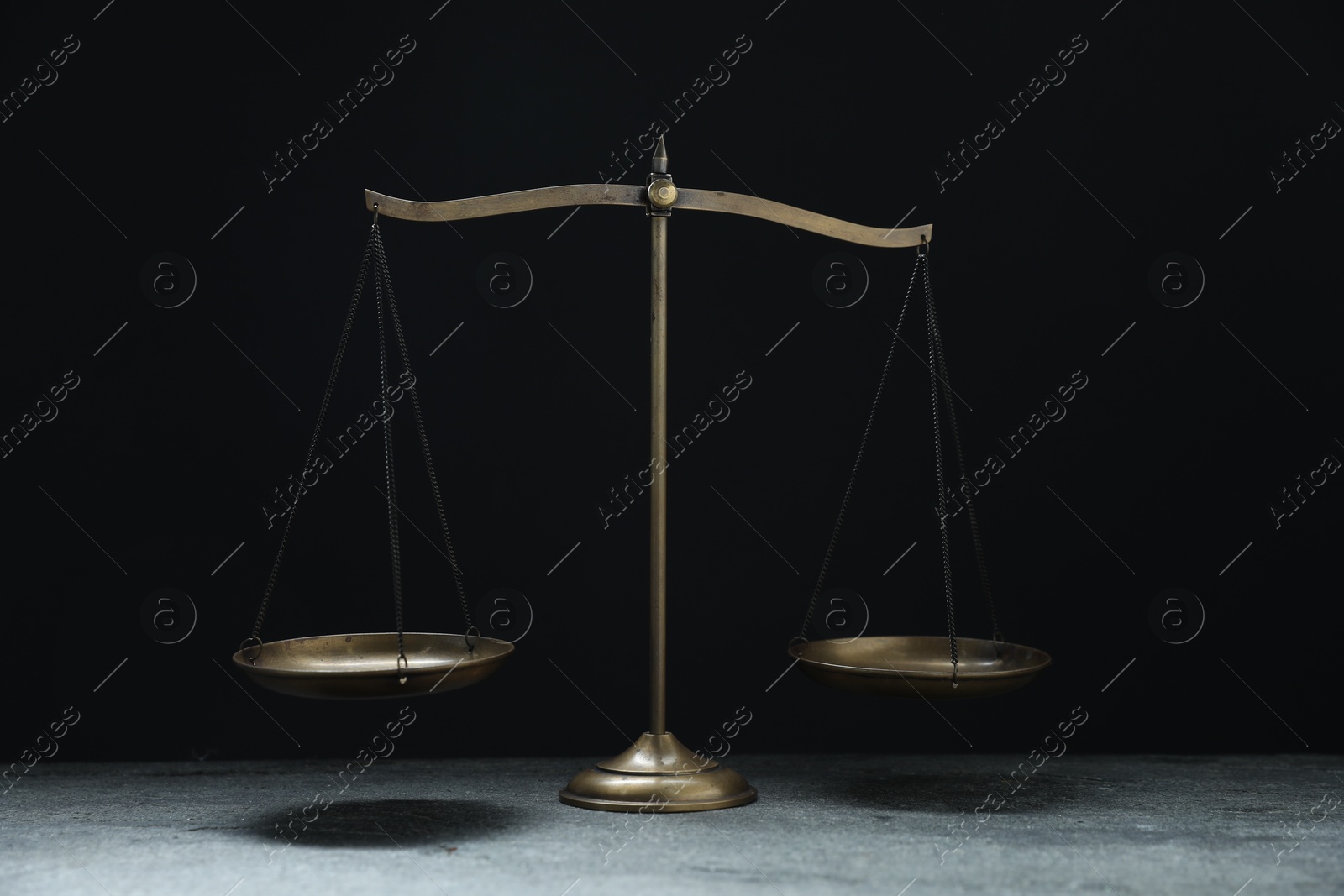Photo of Scales of justice on grey table against black background