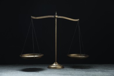 Photo of Scales of justice on grey table against black background