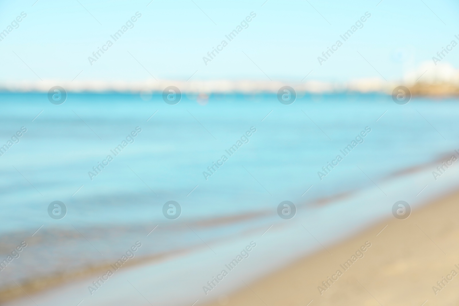 Photo of Beautiful sea and shore under light blue sky, blurred view
