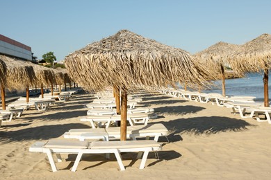 Photo of Straw umbrellas and sunbeds on sandy beach