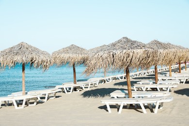 Photo of Straw umbrellas and sunbeds on sandy beach