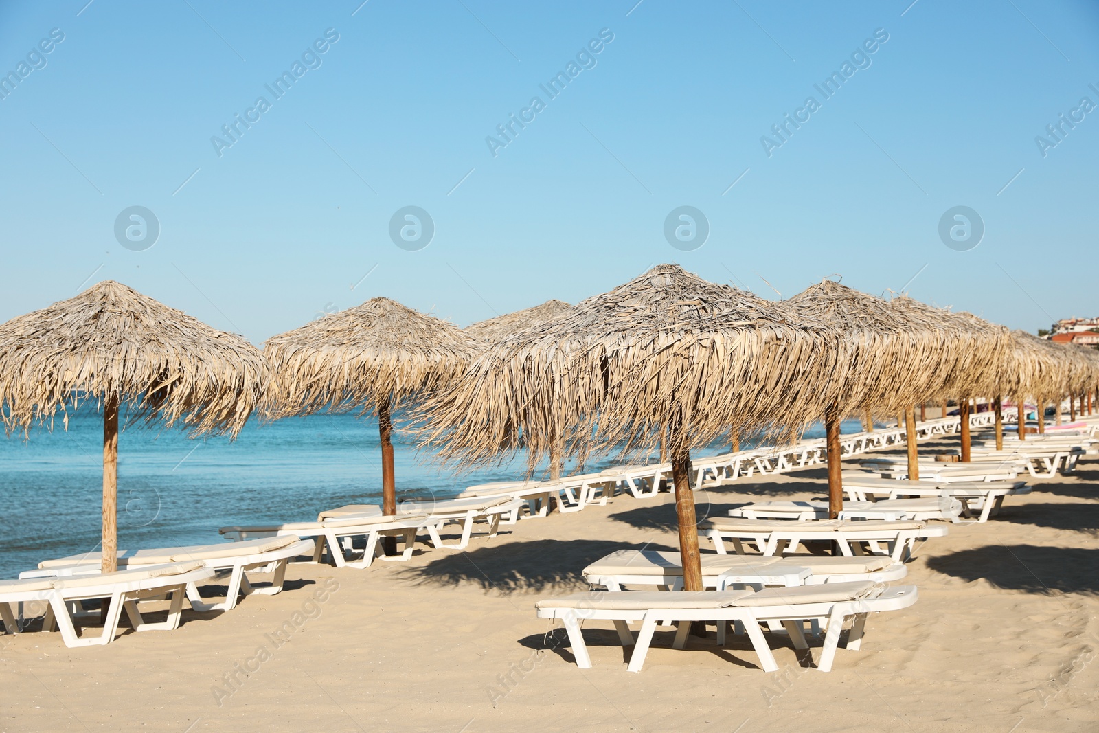 Photo of Straw umbrellas and sunbeds on sandy beach