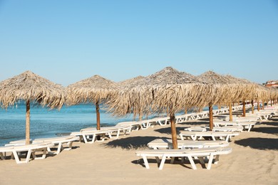 Photo of Straw umbrellas and sunbeds on sandy beach