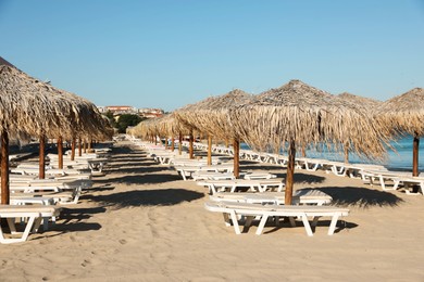 Photo of Straw umbrellas and sunbeds on sandy beach