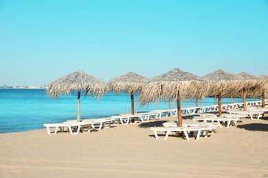 Photo of Straw umbrellas and sunbeds on sandy beach
