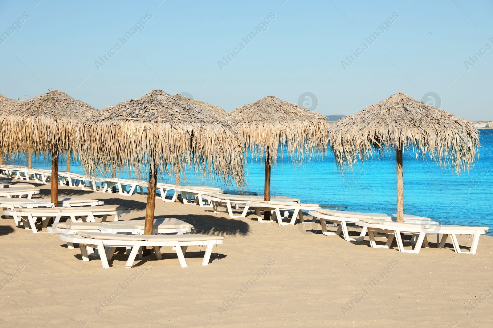 Photo of Straw umbrellas and sunbeds on sandy beach